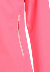 Primer plano de una tela rosa con un bolsillo vertical con cremallera que presenta una lengüeta de tirador rosa claro y un acento gris en la cremallera.