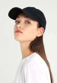 Gorra de béisbol negra con visera curva, hecha de tela suave. Presenta un logo bordado en el frente y una silueta clásica.