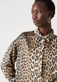 Satin skjorte med leopardprint, der har klassisk krave, knaplukning og lange ærmer med en glat tekstur og en afslappet pasform.