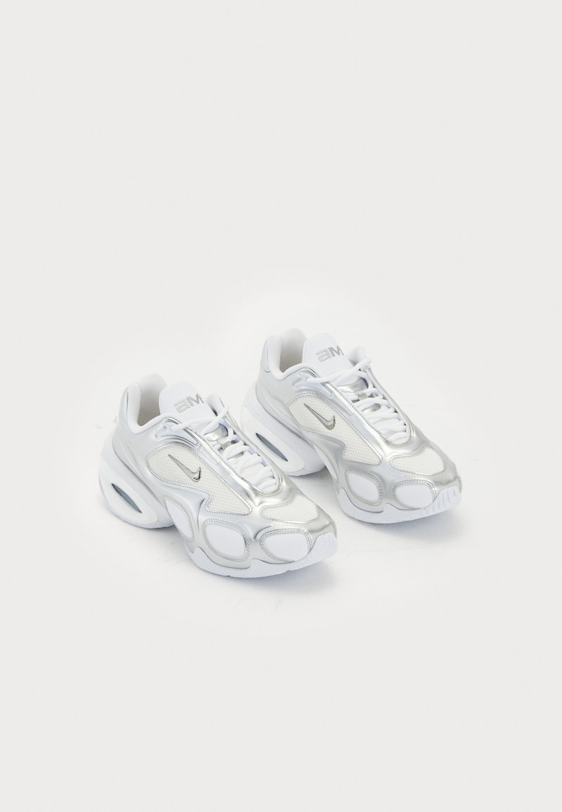 White athletic shoes featuring a mesh upper with silver accents, a unique shape, and air cushioning in the heel. Laced design with logo.