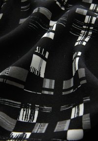 Tissu noir avec un motif plaid géométrique en nuances variées de gris et blanc, avec une texture lisse et un léger éclat.