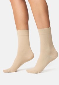 Beige ankelstrømper med en ribbet kant, lavet af et glat, strækbart materiale, med en sømløs tådesignet for komfort.