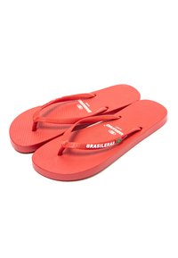 Chanclas de goma roja con suela texturizada, tiras finas y la palabra "BRASILEIRAS" impresa en la tira en blanco.