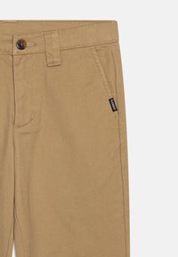 Khaki nadrág, pamut keverék anyagból. Elöl zseb, övhurkok, gombos záródás, és egy kis márkajelzés található az oldalon.