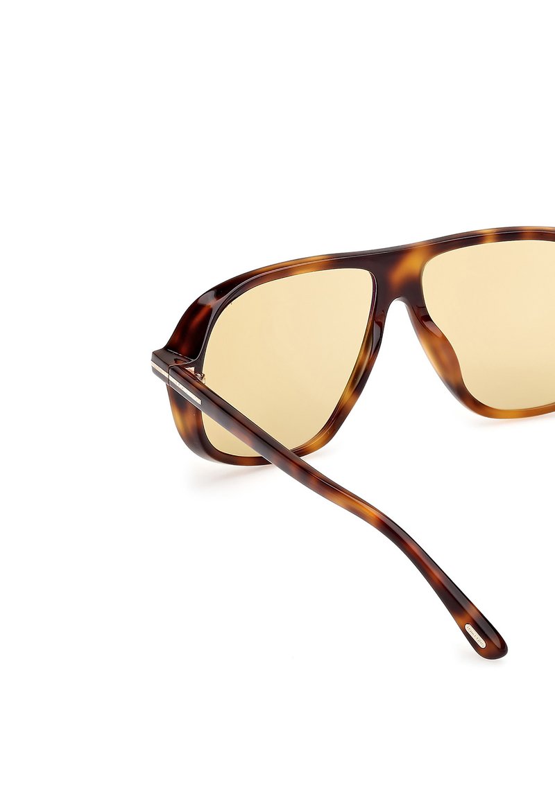 Occhiali da sole in tartaruga marrone con un design audace e angolare, dotati di lenti amber chiare e sottili aste marroni scure.