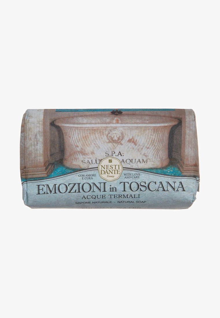 Natural soap bar with a textured paper wrapper featuring artistic imagery of a bath and aqua patterns. Text reads "Emozioni in Toscana."