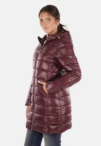 Cappotto imbottito bordeaux con cappuccio, design trapuntato e chiusura con zip. Presenta tasche laterali e polsini elasticizzati; texture lucida e liscia.