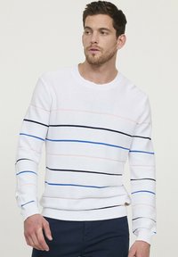 Witte gebreide trui met horizontale strepen in roze, blauw en zwart. Heeft een ronde halslijn en ribgebreide boorden en onderrand.