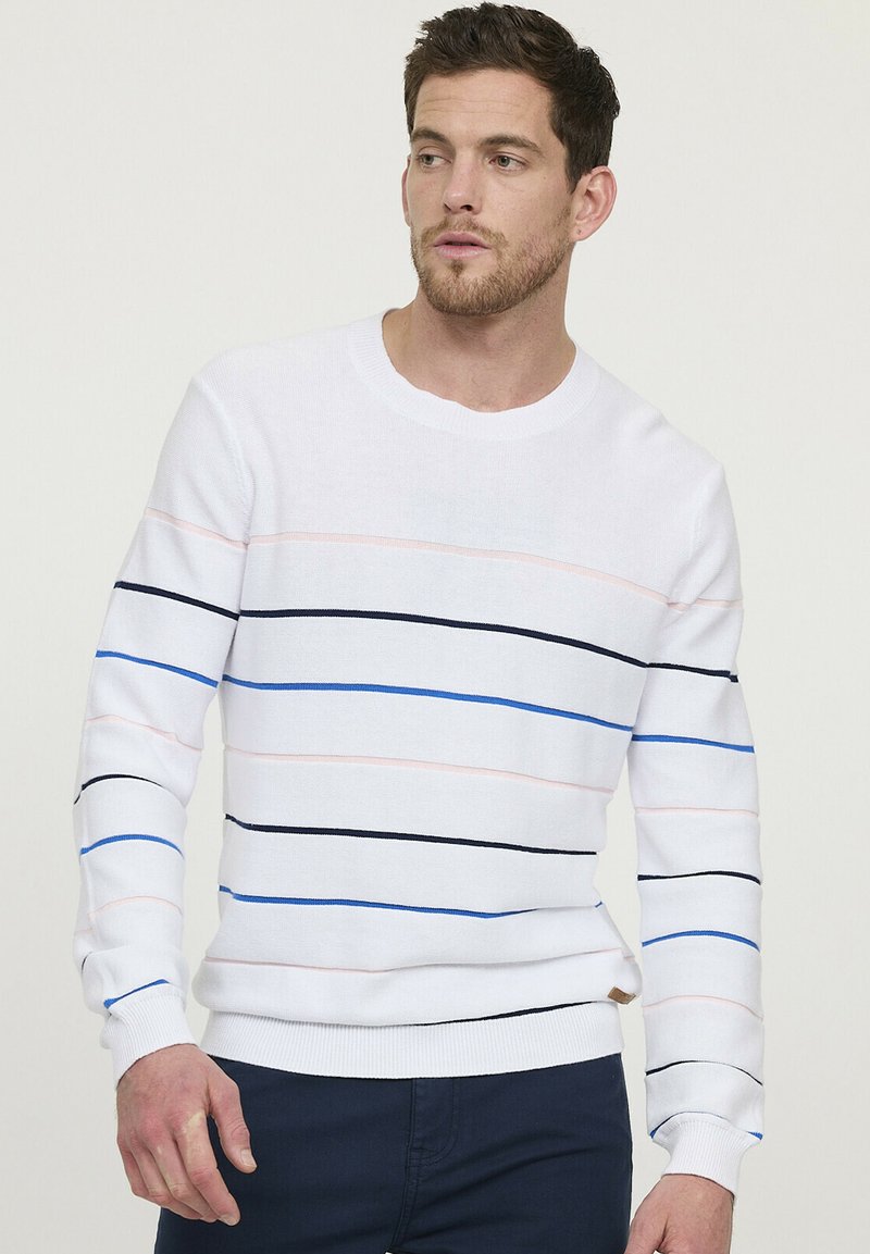 Witte gebreide trui met horizontale strepen in roze, blauw en zwart. Heeft een ronde halslijn en ribgebreide boorden en onderrand.