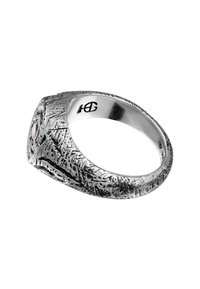 Söljdring med texturerad yta, med en distinkt design och en liten ädelsten som accent. Graverad logotyp synlig på insidan.