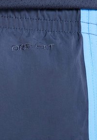 Chalatai jūrinės spalvos su šviesiai mėlynais akcentais, turintys surinktą liemens juostos dizainą. "DRI-FIT" logotipas išsiuvinėtas šiek tiek tamsesne jūrinės spalvos siūle.