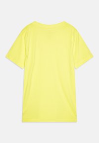 Camiseta de manga corta de color amarillo brillante, fabricada en algodón suave. Presenta un cuello redondo y un diseño simple y sin adornos con una textura suave.