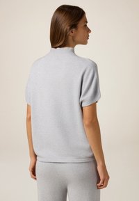 Light gray knit sweater with short sleeves, ribbed collar and hem. Soft texture, relaxed fit, showcasing back view.