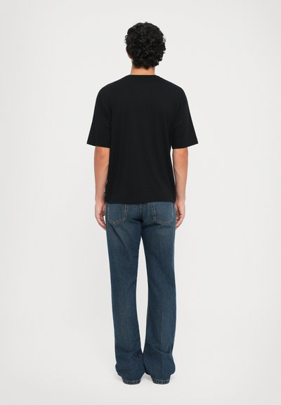 Svart t-skjorte med korte ermer og avslappet passform, kombinert med jeanstype i middels vask med baklommer og rett ben-design.