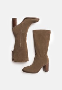 Bottes montantes en daim marron avec un bout carré, une fermeture éclair latérale et un talon en bois empilé. Texture lisse avec un design minimaliste.