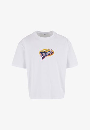 Fehér pamutpóló, középen színes "Welcome to Miami" felirattal, laza szabással és rövid ujjú kivitelben.