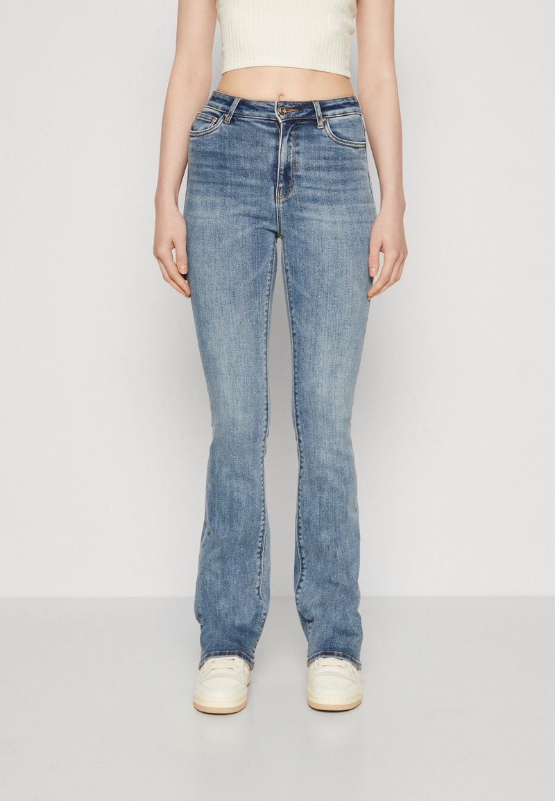 Ljusblå vida jeans i denim med en blekt textur, femficksdesign, bältesöglor och knappgylf. Matchas med en vit croptop.