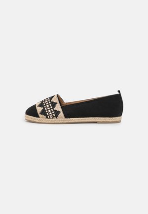 Espadrille plate noire avec motif géométrique beige tissé sur le bout et semelle en jute tressée, présentée sur fond blanc.