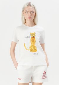 Biele krátke rukávy tričko s ilustráciou leoparda s okuliarmi a textom. Skombinované s bielymi šortkami, ktoré nesú červené logo "REPLAY".