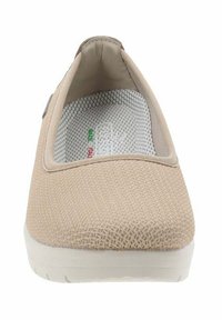 Zapato beige tipo slip-on con parte superior de tela texturizada, cuello elástico y suela de goma blanca. El interior cuenta con un forro de malla para mayor transpirabilidad.