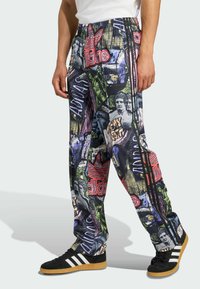 Mehrfarbige Adidas-Hosen mit grafischem Druck, elastischem Bund, seitlichen Streifen und schmal zulaufenden Beinen, ausgestattet mit verschiedenen auffälligen Designs und Texturen.