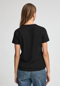 Svart bomull T-shirt med korta ärmar, rund halsringning och avslappnad passform. Tyget verkar mjukt och lätt, perfekt för avslappnad användning.