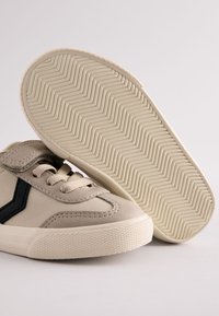 Beežid seemisnahast tennised musta siksakmustriga, millel on tekstureeritud kummist tald ja lamedad paelad. Tald on kalasaba mustriga.