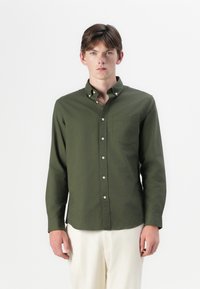 Camicia a maniche lunghe, con bottoni, in cotone verde oliva, dotata di taschino sul petto, colletto alla francese e vestibilità comoda. Bottoni bianchi e tessuto uniforme.