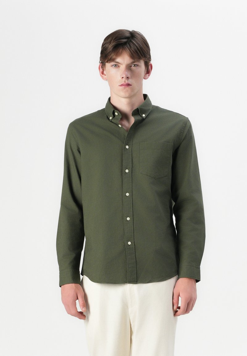 Camicia a maniche lunghe, con bottoni, in cotone verde oliva, dotata di taschino sul petto, colletto alla francese e vestibilità comoda. Bottoni bianchi e tessuto uniforme.