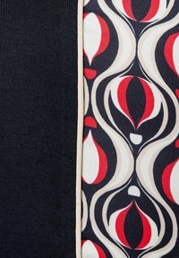 Tela impresa con un audaz patrón floral en rojo y crema sobre una sección acanalada azul marino, bordeada por un ribete beige.