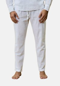 Pantalons en lin blanc avec une coupe décontractée, taille élastique à cordon de serrage et ourlets retroussés. Le tissu a une surface texturée, améliorant la respirabilité.