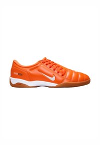 Chaussures de football orange avec une tige en cuir lisse, des coutures texturées et un swoosh Nike blanc. Elles possèdent une semelle en caoutchouc marron et des lacets.