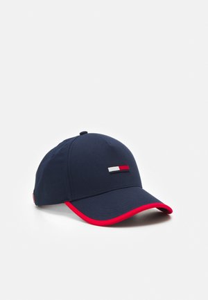 Marineblauwe baseballpet met rode bies langs de klep en een klein rechthoekig rood, wit en marineblauw logo op het voorpaneel.