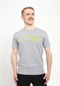 Grå bomulds T-shirt med et flerfarvet grafisk tryk "JT Racing USA" på brystet. Kortærmet og med rund hals.