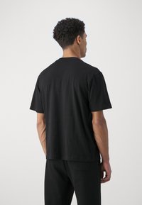 Zwarte katoenen t-shirt met korte mouwen, ronde hals en een relaxte pasvorm. Gladde textuur, minimalistisch ontwerp, geen zichtbare patronen of accenten.