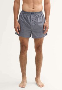 Heren geruite boxershorts in marineblauw en wit, met een elastische tailleband, enkele knoopsluiting en zijsplitten voor meer bewegingsvrijheid.