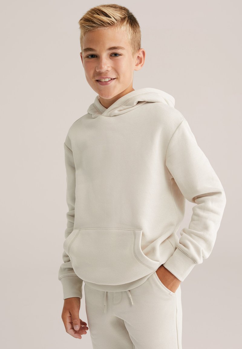 Felpa con cappuccio di un beige chiaro, realizzata in morbido tessuto, con tasca a marsupio e polsini a costine, abbinata a pantaloni jogger coordinati.