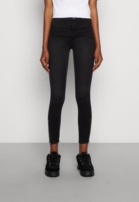 Jeans skinny pretos de cintura alta com uma textura lisa e suave, detalhes com fecho de correr nos tornozelos e um design ajustado.