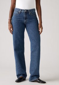 Brede jeans in donkerblauwe denim met een hoge taille, voorzien van een knoop- en ritssluiting, vijf zakken en rechte pijpen.