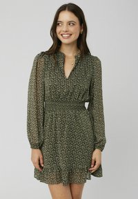 Robe florale verte avec de longues manches bouffantes, une taille smockée et un ourlet froncé. Fabriquée dans un matériau léger et transparent avec une texture douce.