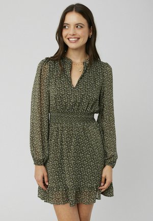 Robe florale verte avec de longues manches bouffantes, une taille smockée et un ourlet froncé. Fabriquée dans un matériau léger et transparent avec une texture douce.