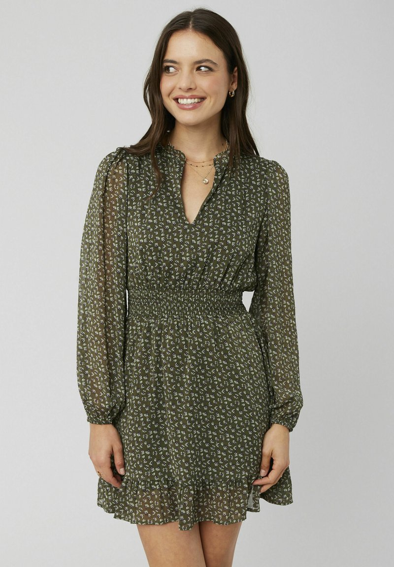 Robe florale verte avec de longues manches bouffantes, une taille smockée et un ourlet froncé. Fabriquée dans un matériau léger et transparent avec une texture douce.