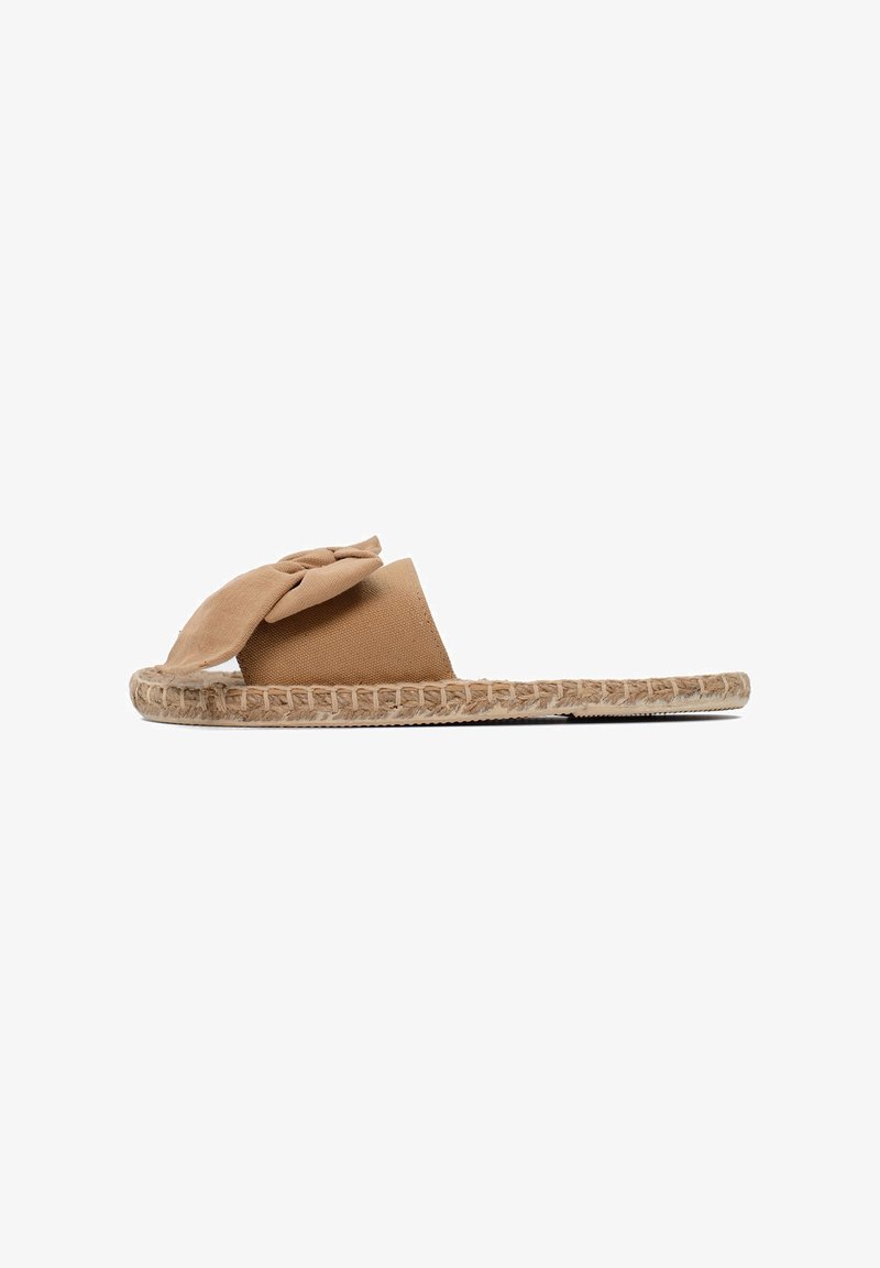 Sandalo espadrilles beige con un grande fiocco decorativo, realizzato in tessuto morbido. Presenta una suola in juta intrecciata e un design piatto.