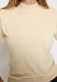 Beidzis, ribots adīts džemperis ar augstu apkakli un raglāna piedurknēm. Mīksta tekstūra, pieguloša forma, piemērots kārtu veidošanai.