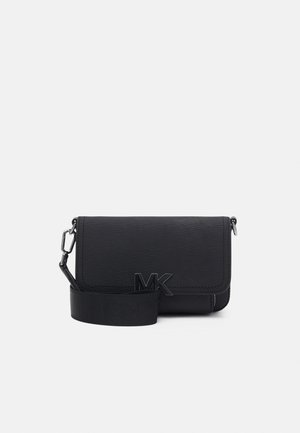 Sac bandoulière en cuir noir texturé avec fermeture à rabat, large bandoulière et logo MK en métal à l'avant.