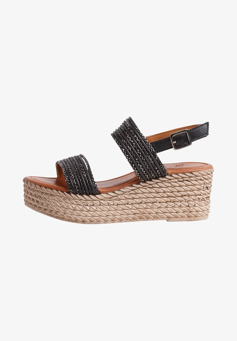 Sandales compensées noires avec un design à lanières en tissu texturé, semelle en corde tressée et bride réglable à la cheville.