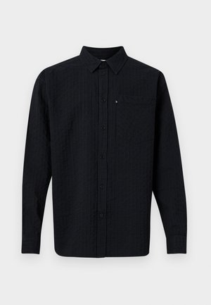 Camicia nera a maniche lunghe con colletto, caratterizzata da un motivo a righe verticali testurizzate e una tasca sul petto. Chiusura con bottoni sul davanti.