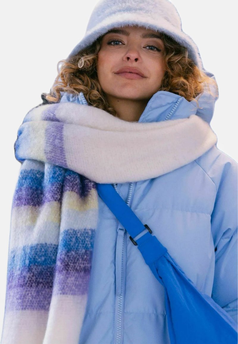 Light blue puffer jacket, white scarf with multicolored stripes, and a blue crossbody bag. Soft textures and vibrant patterns.