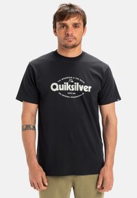 Černé bavlněné tričko s bílým grafickým logem "Quiksilver" a textem pod ním. Krátké rukávy, kulatý výstřih a volný střih.