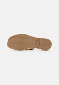 Brown rubber sole with textured grip patterns and embossed branding. Flat design with a smooth finish and subtle stitching details.